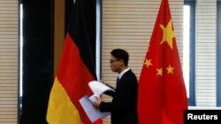 资料照:在北京举行中德经贸部长会议期间一名男子走过中国和德国国旗。(2016年11月1日)