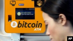 一名女子走过香港街头的比特币提款机。(2017年12月21日)