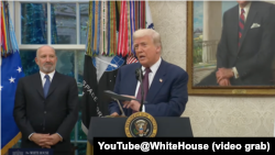 美国总统唐纳德·特朗普在白宫椭圆形办公室与苹果首席执行官蒂姆·库克共同出席一场活动时,手上拿了一个B-2轰炸机模型。(2025年8月6日)