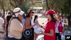 资料照片:希腊雅典的红十字会志愿者向游客发放饮用水。(2024年7月17日)