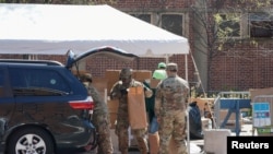 疫情期间,美国陆军国民警卫队员在纽约市曼哈顿哈莱姆区向民众分发由多家市政府机构提供的免费食物。(2020年4月15日)