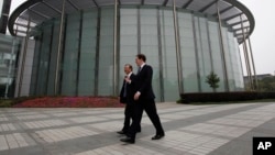 英国财政大臣乔治•奥斯本与华为公司CEO和创始人任正非在深圳参观华为总部会晤之前一道走过一座会议厅。(2013年10月16日)