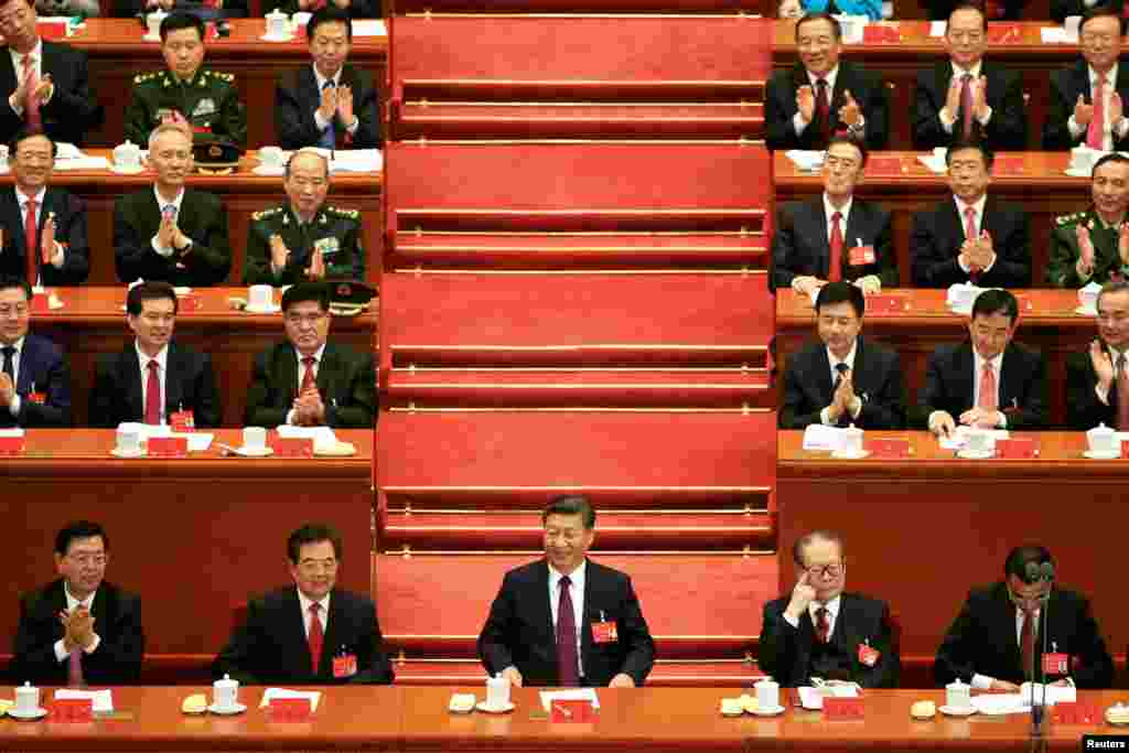 中国共产党第十九次全国代表大会在中国北京人民大会堂开幕。主席台前排从左至右依次是:全国人大常委会委员长张德江,中国前国家主席胡锦涛,中国国家主席习近平,前主席江泽民,国务院总理李克强(2017年10月18日)。照片上,这5个人里只有张德江仍然在鼓掌,而主席台上后面的人除了3人之外都在鼓掌,其中有习近平的亲信、北京市委书记蔡奇,以及国务委员杨洁篪、外交部长王毅等人。