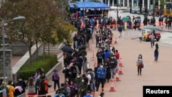 2022年2月8日在香港中区,市民戴着口罩在一个临时的露天新冠病毒核酸检测中心排队
