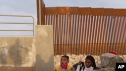 在亚利桑那州尤马市,一个海地移民家庭正从靠近美国边境墙缺口的一条岩石运河中走出来。(2021年6月9日)