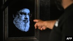 2024年9月28日,贝鲁特黎巴嫩私营电视台NBN播出节目时,一名男子指着电视机上的真主党已故领导人哈桑·纳斯鲁拉(Hassan Nasrallah)照片。