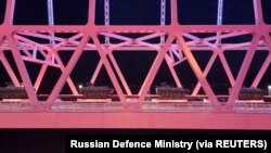 俄罗斯国防部2022年2月16日发布的录像截图显示,一列货运火车运载着多辆俄军军车通过一座桥梁从克里米亚半岛开往俄罗斯内地。