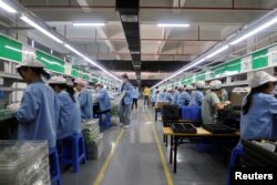 中国广东东莞的工人为一家美国公司的RiotPWR移动游戏控制器在生产线上工作。(2021年12月7日)