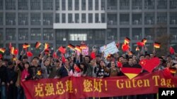 资料照:中国安徽省合肥市的德国大学学生们手持中德横幅和中德国旗等待德国时任总理默克尔的访问。 (2015年10月30日)