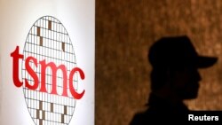 资料照:2014年7月16日,在台北的一次投资会议期间一名保安站在台积电标识旁。(路透社照片)