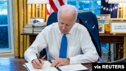 (资料照片)2022年2月21日美国总统拜登在白宫签署行政命令,禁止美国个人与被俄罗斯承认为独立的乌克兰东部两个分离地区之间的贸易和投资。