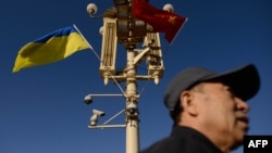 资料照:一名男子走过北京天安门广场灯柱上悬挂的中国与乌克兰国旗。(2013年12月5日)