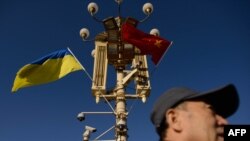 资料照:一名男子走过北京天安门广场灯柱上悬挂的中国与乌克兰国旗。(2013年12月5日)