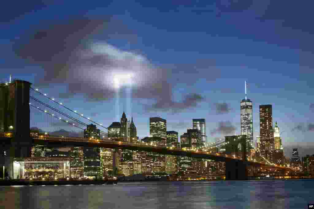 The Tribute in Light rises behind the Brooklyn Bridge and buildings adjacent to the World Trade Center complex, Sept. 10, 2014 in New York.