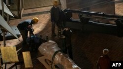 法新社照片:在香港大学,工人移除丹麦艺术家高志活纪念1989年天安门镇压事件受害者的雕塑“国殇之柱”的一部分,搬往一座集装箱。(2021年12月23日)