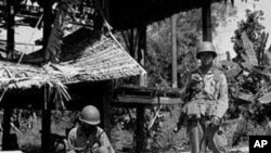 一名柬埔寨农民坐在一个骷髅旁,这是遭到红色高棉屠杀的平民的遗骨(资料照)