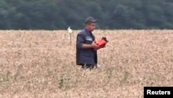 ကယ်ဆယ်ရေးအလုပ်သမားတစ်ဦး ပျက်ကျလေယာဉ်က Data recorder ကို သယ်ဆောင်လာစဉ်။