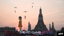 ကမ္ဘာကျော် Squid Game တောင်ကိုရီးယား တီဗွီစီးရီးစ်ထဲက ဇာတ်ရုပ် ၁၂ မီတာ (၃၉ ပေကျော်) အမြင့်ရှိတဲ့ ယောင်ဟီးအရုပ်ကို ထိုင်းနိုင်ငံ ကျောက်ဖရားမြစ်ထဲမှာ ကြော်ငြာသရုပ်ပြလှည့်လည်နေစဥ်။ (ဒီဇင်ဘာ ၁၉၊ ၂၀၂၄)