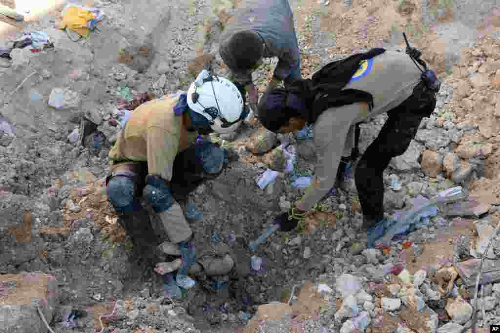 In this photo provided by the Syrian Civil Defense group known as the White Helmets, shows members of Civil Defense removing a dead body from under the rubble after airstrikes hit in Aleppo, Sept. 24, 2016.