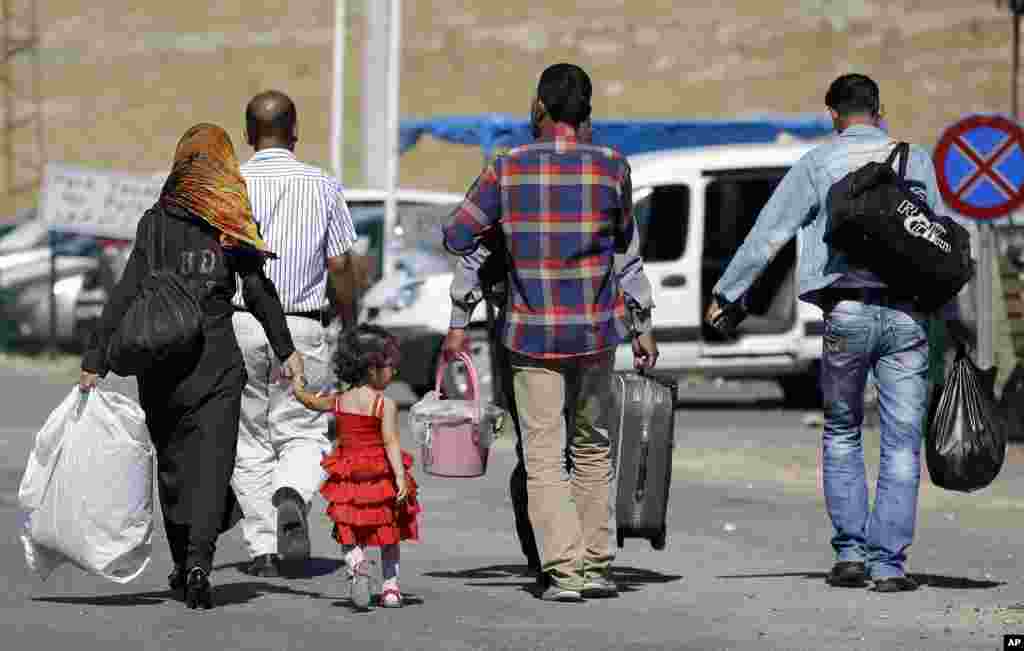 Backdropped by Kobani, in Syria, a Turkish forces armored vehicle patrols the border road in Mursitpinar, on the outskirts of Suruc, on the Turkey-Syria border, Oct. 14, 2014.