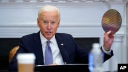 2021年4月12日在华盛顿白宫举行的有关半导体和供应链产业韧性的CEO峰会上,美国总统拜登举起一块硅片。