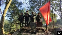 资料照片:缅甸民族民主同盟军成员在缴获的一辆缅甸陆军装甲车上举旗合影。(2023年10月28日)