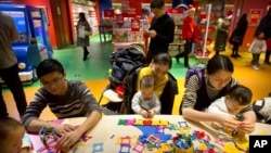 资料照片:在北京哈姆雷斯(Hamleys)玩具店内,家长和孩子们在活动站一起玩耍。(2017年12月23日)