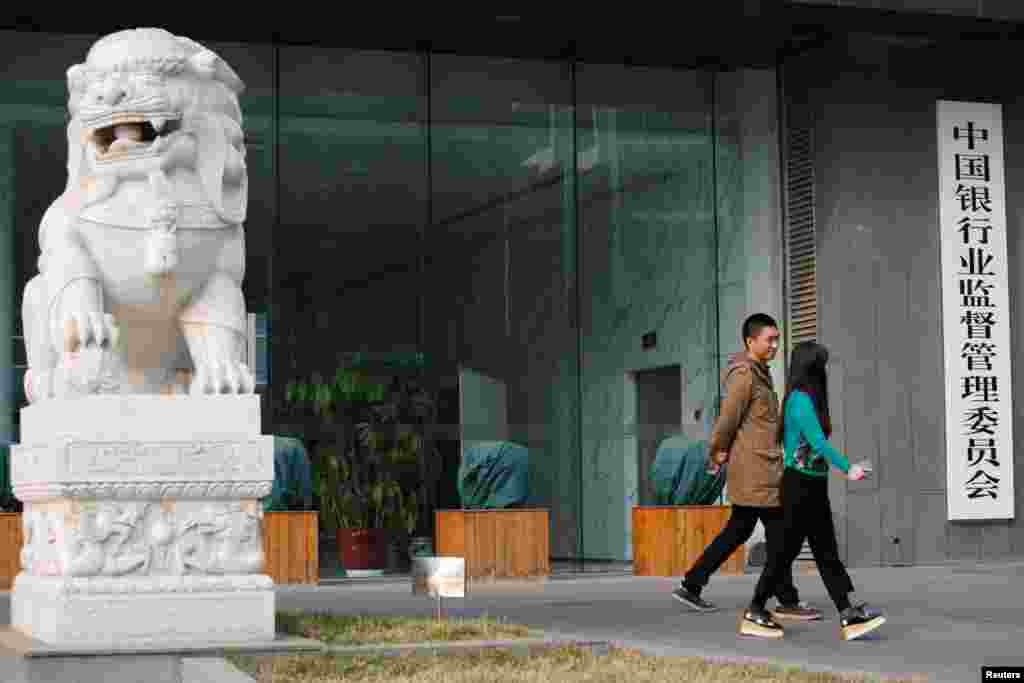 2018年3月13日,北京,中国银行业监督管理委员会(银监会)的大门,标牌、石狮子和行人。人大通过了国务院机构改革方案,包括组建中国银行保险监督管理委员会,不再保留银监会和保监会,将这两个机构拟定银行业、保险业重要法律法规草案和审慎监管基本制度的职责划入中国人民银行。而民间说是银监会和保监会合二为一。