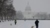 Orang-orang berjalan-jalan dengan anjingnya di sepanjang National Mall saat salju turun selama badai musim dingin di Washington, D.C., 6 Januari 2025.
