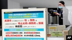 日本成田国际机场的工作人员在调整体温监测仪以测试从中国武汉和其他城市抵达的旅客健康状况。(2020年1月23日)