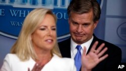 美国联邦调查局局长克里斯托弗·雷在白宫的一个例行记者会上倾听国土安全部部长吉尔斯腾·尼尔森(左)讲话。(2018年8月2日)