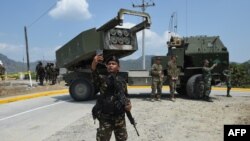 一名菲律宾士兵在参加美菲联合军演后在高机动多管火箭系统(HIMARS) 前用手机自拍。(2016年4月14日)