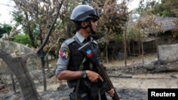 A police officer guards near a house which was burnt down during the last days of violence in Maungdaw, northern Rakhine State, Myanmar August 30, 2017.