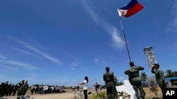 2015年5月11日,一个菲律宾居民和菲律宾军人一起在南中国海的斯普拉特利群岛(南沙群岛中的派格阿萨岛(中业岛)举行升旗仪式。(资料照片)