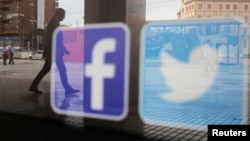 资料照:一家商店的橱窗上映照着推特和脸书的标识。