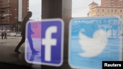 资料照:一家商店的橱窗上映照着推特和脸书的标识。