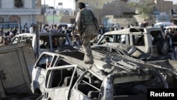 胡塞叛军人员走过被空袭炸坏的汽车。