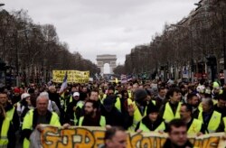 FILE - Yellow Vests protesters march on the Champs Elysees avenue in Paris.