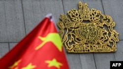 拥护北京的香港人举着中华人民共和国国旗在英国驻香港总领事馆外抗议英国允许持有英国国民海外护照的香港人移居英国,中国国旗旁边可见英国皇家徽章。