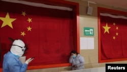 2020年2月27日,武汉一座体育馆改建的医院,一名医护人员试图安抚病患