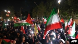 2024年4月14日,伊朗对以色列发动无人机和导弹袭击后,示威者聚集在英国驻德黑兰大使馆前,挥舞着伊朗国旗和巴勒斯坦国国旗。