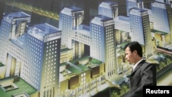 资料照:一名男子走过北京街头张贴的一个新开楼盘的广告牌。
