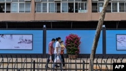 2020 年 9 月 28 日,戴着口罩的行人从仍然关闭的武汉华南海鲜批发市场旁走过。(法新社)