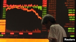 中国安徽省阜阳市的一名投资者站在股票交易所的电子屏幕前(2015年7月27日)