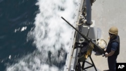 资料图片:2023年5月19日星期五,一名美国海军水手在霍尔木兹海峡的保罗·汉密尔顿号航空母舰上的机枪旁站岗。 (美联社图片)