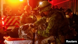 墨西哥消防人员在华雷斯城移民设施发生火灾后在现场救治伤员。(2023年3月28日)