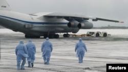 身穿防护服的俄罗斯医务人员走向从中国武汉撤回俄罗斯与东欧国家侨民的军机。(2020年2月5日)