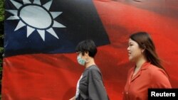 人们从台北街头的台湾旗帜旁走过。(2020年8月10日)