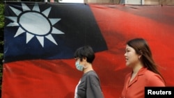 人们从台北街头的台湾旗帜旁走过。(2020年8月10日)