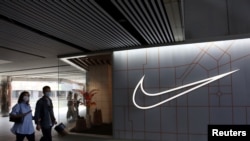 在中国北京的一个购物中心,人们走过体育用品零售商耐克公司的商店(2021年3月25日)。